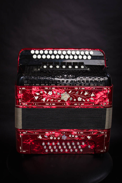 Russian folk instruments. Red bayan on a black background. Russian accordion  - Photo, Image