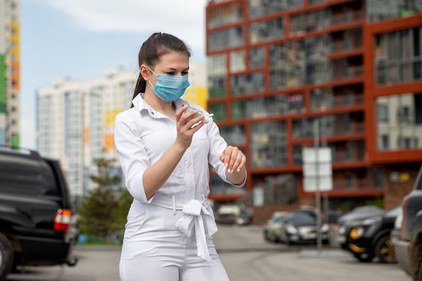 girl in a medical mask and an antiseptic. girl in a medical mask on the street - Фото, зображення