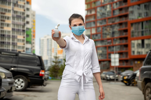 girl in a medical mask shows an antiseptic. focus on antiseptics.  - Photo, image