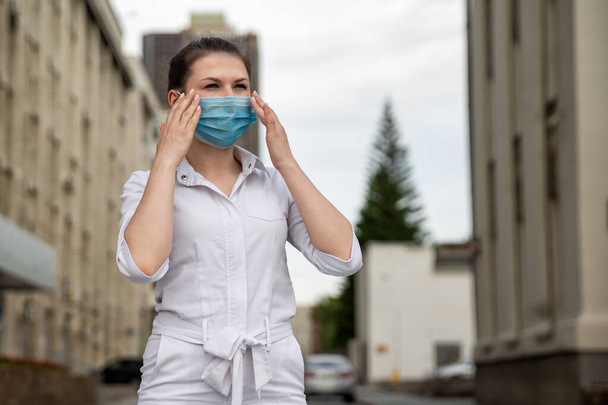 girl in a medical mask on the street. girl in a medical mask in the city. girl 20-29 years old - Фото, зображення
