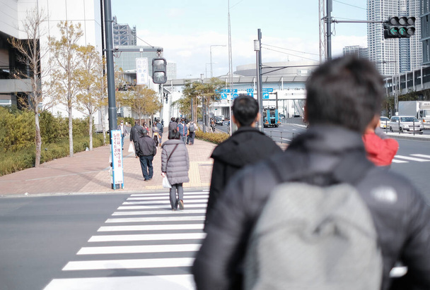 City life in Tokyo, Japan with people walking on sidewalk at noon - Photo, Image