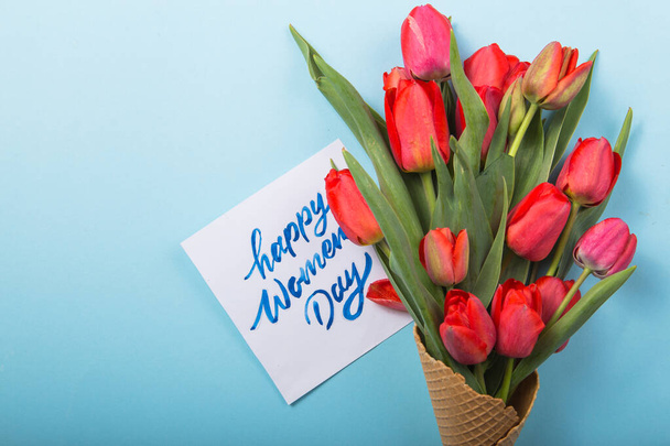 red  beautiful tulips in an ice cream waffle cone with card Womans Day on a concrete background. Conceptual idea of a flower gift. Spring mood - Foto, imagen