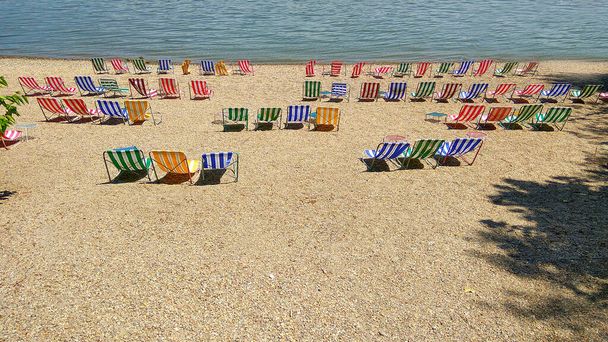 ビーチでビーチチェア。海の近くの砂浜の小石のビーチの椅子。観光のための夏休みと休暇の概念。刺激的な夏の風景。ビーチでリラックス - 写真・画像