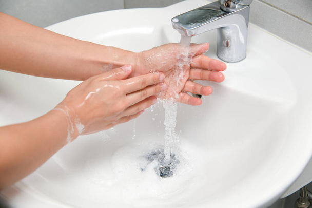 Kobieta używa mydła i myje ręce pod kranem. Koncepcja higieny szczegółowy opis strony. - Zdjęcie, obraz