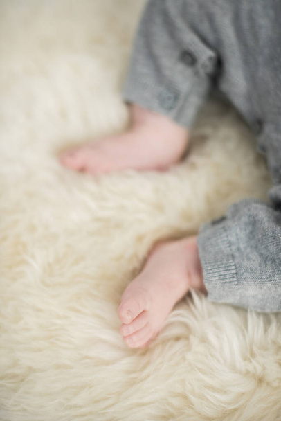 A beautiful soft delicate warm young baby foot photographed with a shallow depth of field. gentle calm colours and feel. baby care and well being. babies feet on a cream fur rug. - Photo, Image
