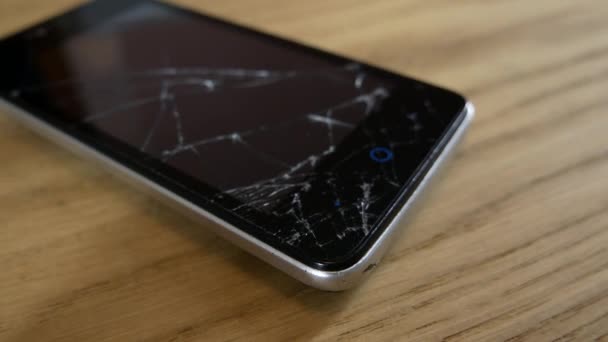 Ένα κινητό τηλέφωνο με σπασμένη οθόνη βρίσκεται σε ένα τραπέζι - Πλάνα, βίντεο
