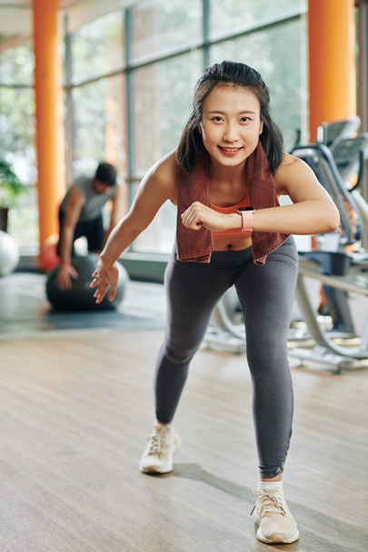 Sonriendo bastante joven mujer asiática inclinándose hacia delante y moviéndose hacia atrás en la pierna - Foto, imagen