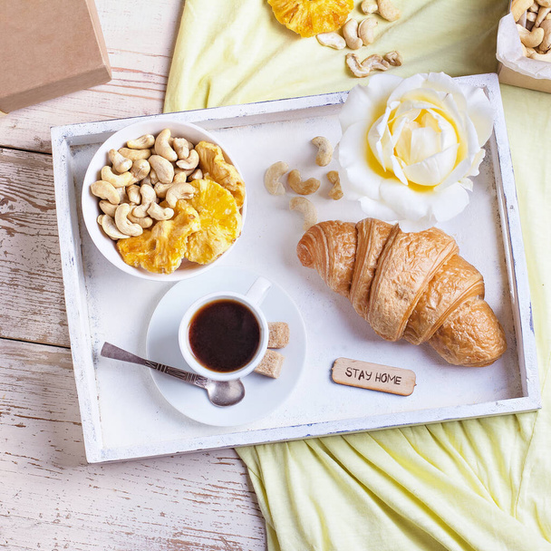 Сніданок на підносі: кава еспресо, круасан та миска з сухофруктами та горіхами
 - Фото, зображення