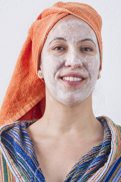 Uma mulher aplying uma máscara a seu rosto e ter o divertimento - Foto, Imagem