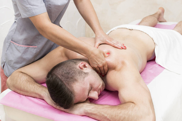 Sports wellness massage is given to a man athlete with a massage parlor. - Photo, image