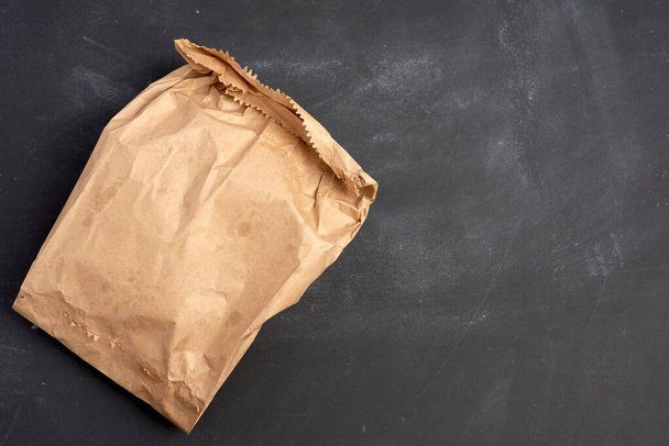 brown paper bag on a black background, top view, place for an inscription - Zdjęcie, obraz
