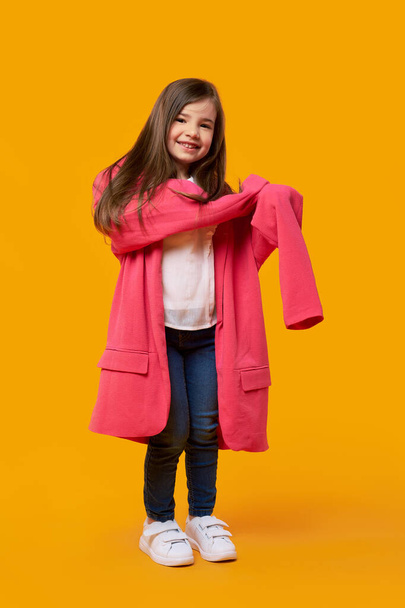 Happy young girl wearing jacket of her mother and fooling around - Foto, Imagem