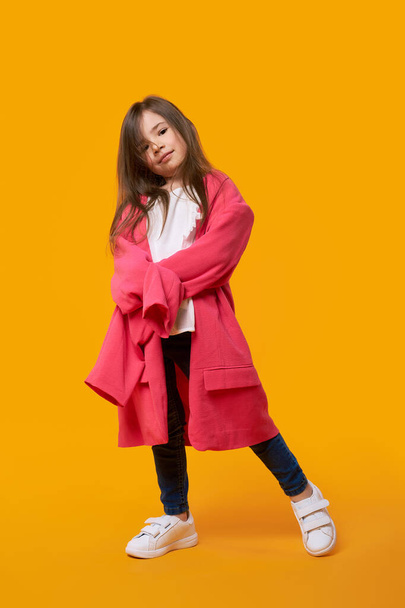 Happy young girl wearing jacket of her mother and fooling around - 写真・画像