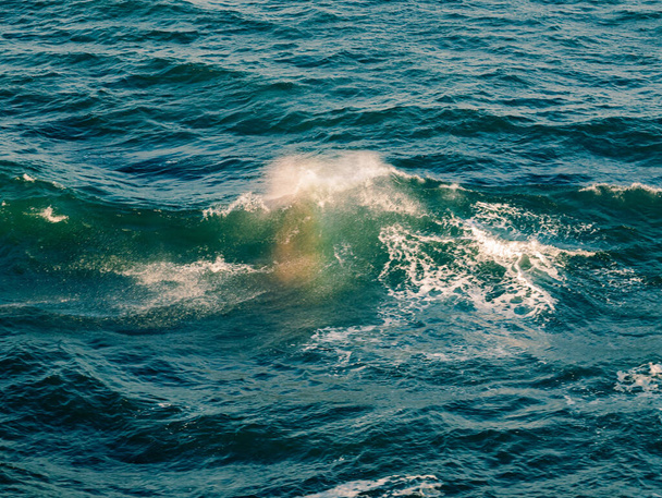 Valtameren aallot sateenkaaren kanssa kesäauringossa
 - Valokuva, kuva