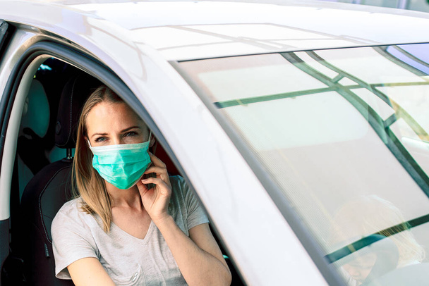 Vermoeide verpleegster die in haar auto naar huis reed van de nachtdienst, vechtend tegen een pandemie. Een verdrietig meisje met een masker dat wegkijkt. Coronavirus pandemische achtergrond met kopieerruimte. Afsluiten. Voorjaarsallergie - Foto, afbeelding