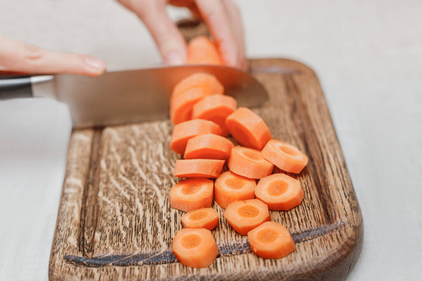 Cortar zanahorias y otras verduras con un cuchillo de cocina en una tabla de madera
 - Foto, imagen