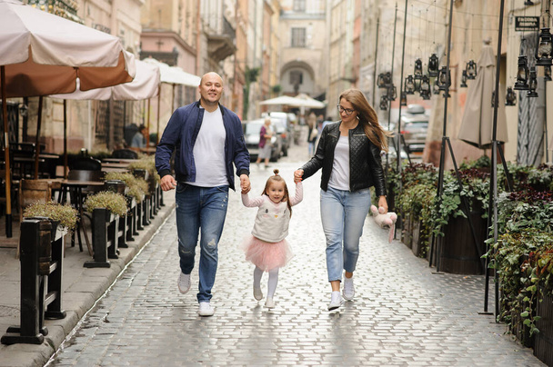 Dwoje rodziców z małą córeczką spaceruje ulicami starego miasta. - Zdjęcie, obraz