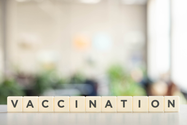 white cubes with vaccination lettering on white desk, covid-19 concept - Photo, Image