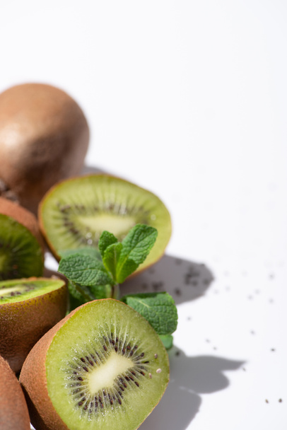 selective focus of kiwi fruit halves near peppermint leaves on white - 写真・画像