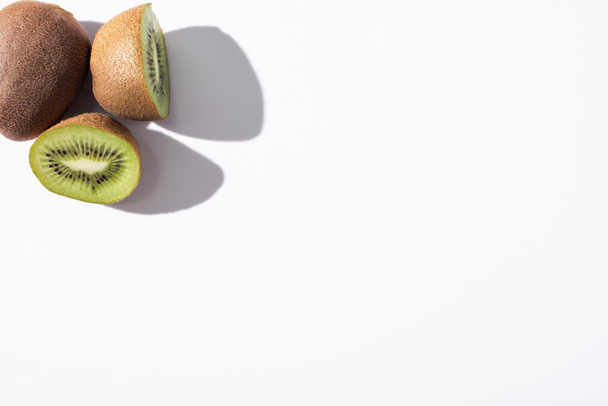 top view of whole kiwi fruit near halves on white with copy space  - Photo, Image