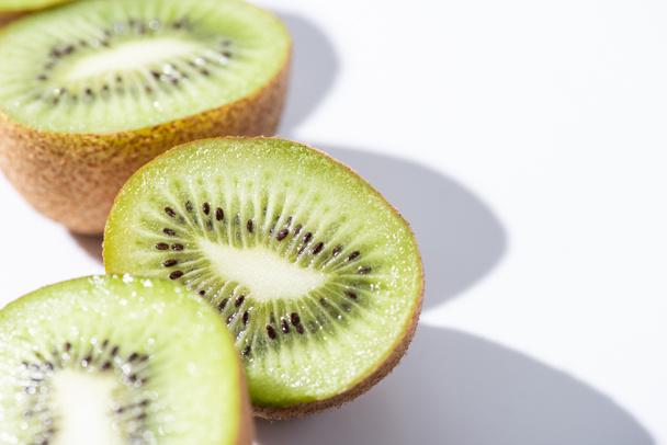 selective focus of green kiwifruit halves on white  - 写真・画像