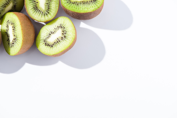 top view of fresh and ripe kiwifruit halves on white  - Foto, Bild