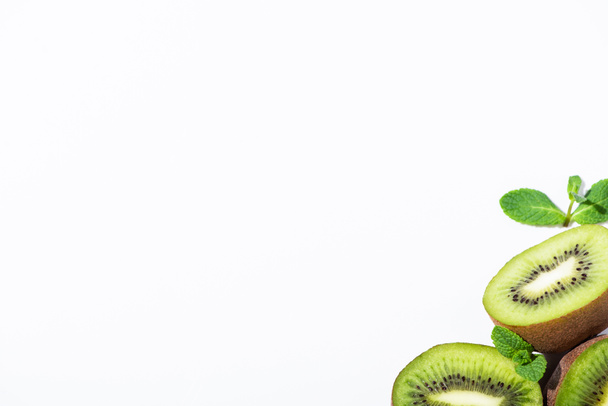вид зверху стиглих і зелених ківі фруктових половинок біля м'яти м'яти ізольовані на білому
  - Фото, зображення