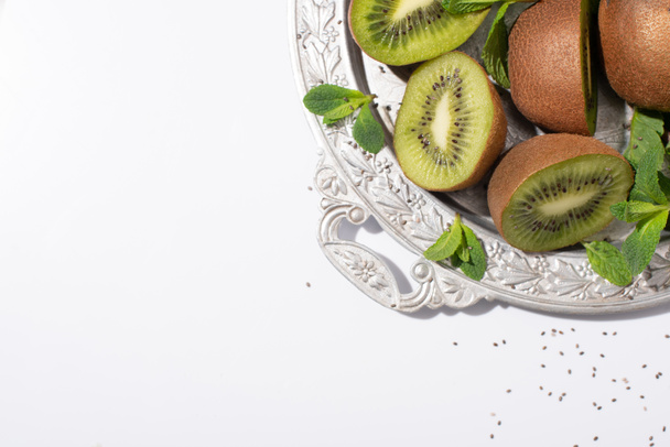 top view of juicy kiwi fruits near green peppermint on silver plate on white - Foto, Imagem