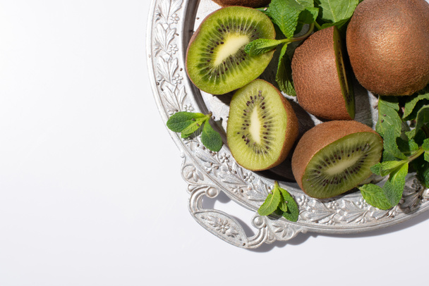 top view of tasty kiwi fruits near fresh peppermint on silver plate isolated on white - Fotoğraf, Görsel
