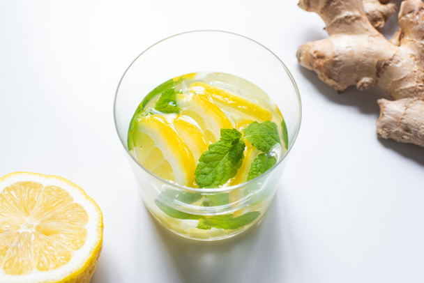 friss limonádé üveg közelében citrom és gyömbér gyökér fehér alapon - Fotó, kép