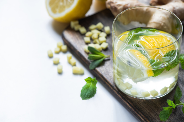 enfoque selectivo de limonada de jengibre fresco en vidrio con limón y menta sobre tabla de madera sobre fondo blanco
 - Foto, Imagen