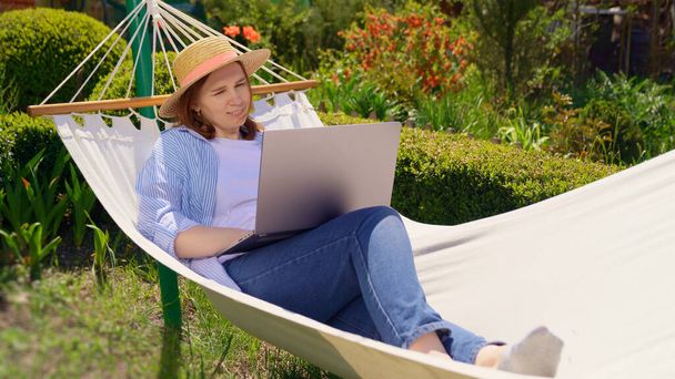 mujer se encuentra en la hamaca y el trabajo en el ordenador
 - Foto, imagen