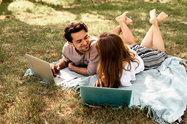 A beautiful teen couple man and women working use laptop to working at outdoor park holiday - Fotó, kép