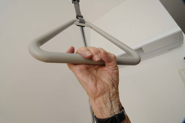 Cuidados paliativos para pessoas com condições crônicas, mão segurando uma alça na cama do hospital
 - Foto, Imagem