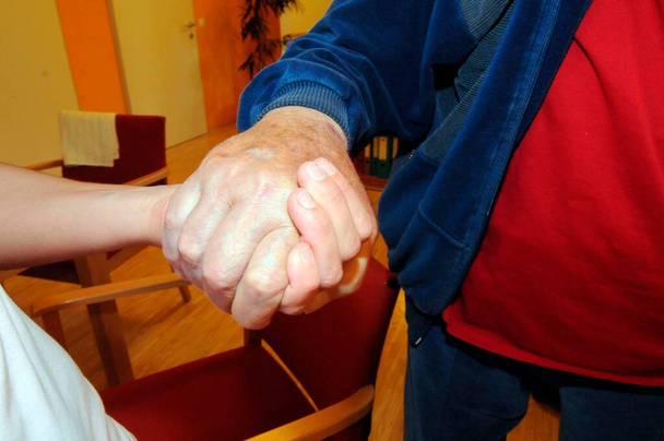 Palliatieve zorg voor mensen met chronische aandoeningen, persoon die een patiënt hand - Foto, afbeelding