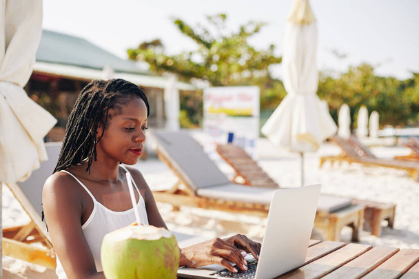 blogger concentrata femminile seduta a tavola sulla spiaggia e al lavoro su articolo o post sul blog
 - Foto, immagini
