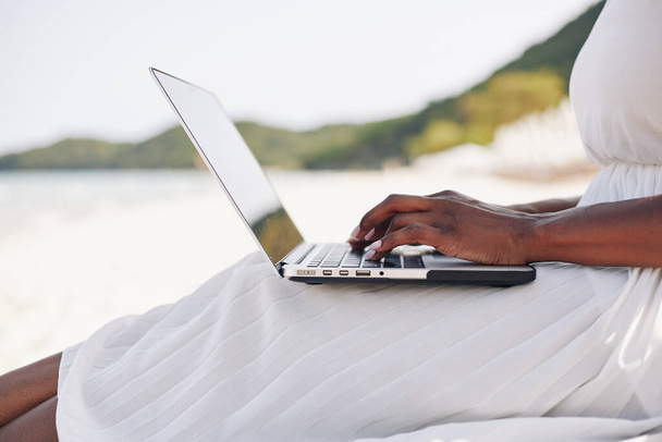 Vrouwelijke freelancer zittend op het strand van tropisch eiland en werkend op laptop - Foto, afbeelding
