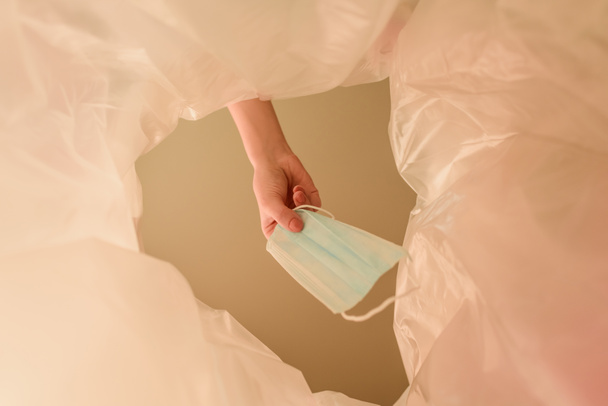 Ausgeschnittene Ansicht einer Frau, die medizinische Maske in Mülleimer wirft, Ende des Quarantäne-Konzepts  - Foto, Bild