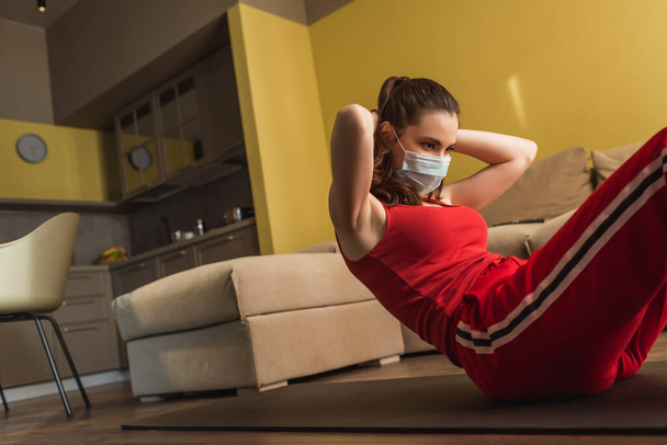 young woman in medical mask and sportswear working out on fitness mat  - Valokuva, kuva