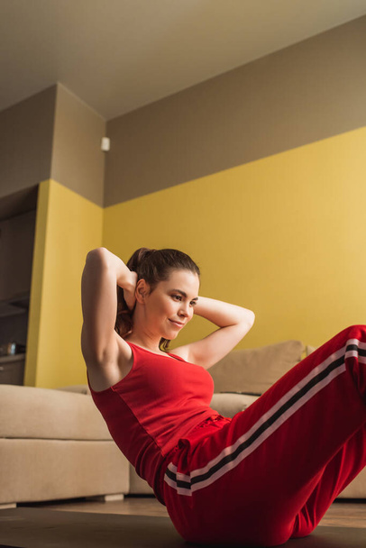 mujer alegre en ropa deportiva haciendo ejercicio en la alfombra de fitness
  - Foto, imagen