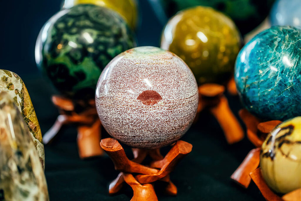 Piedra en forma de esfera con una marca como labios en el soporte. Varias piedras minerales gemas
 - Foto, Imagen
