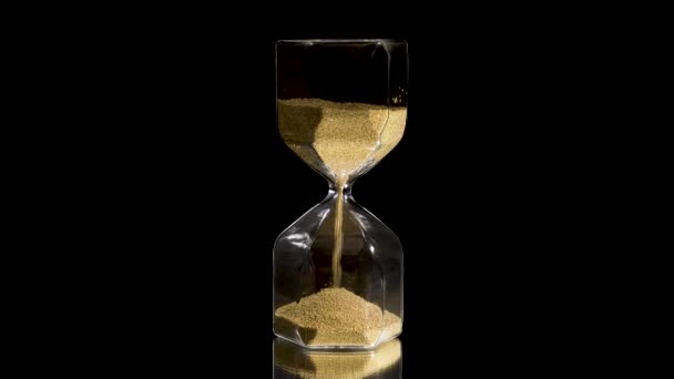 Elegant and stylish bronze transparent sandglass with trickling golden round particles. Stock footage. Sandglass isolated on black background, time, hurry up, last minute, no time concepts. - Footage, Video