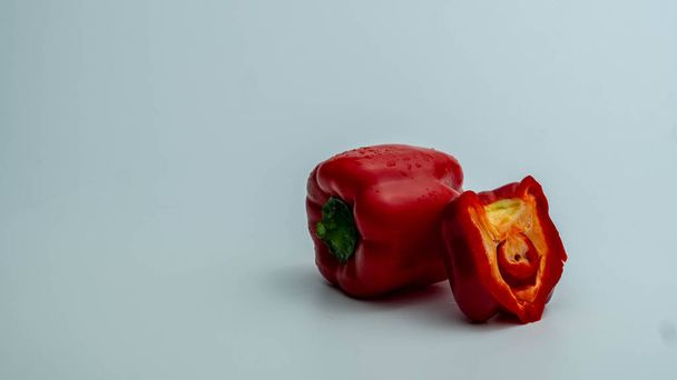 Red bell pepper with chopped portion on gray gradient background on the right side of the frame - Zdjęcie, obraz