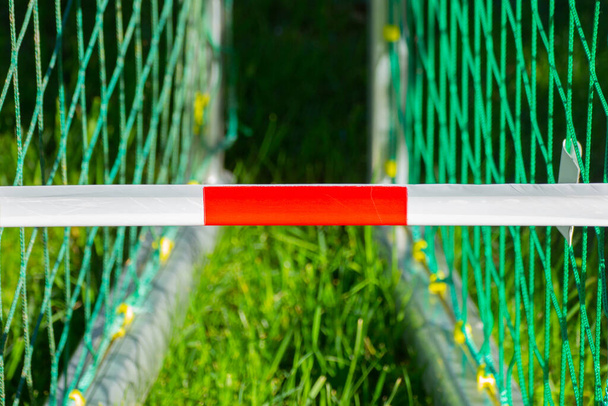 Fita de barreira vermelha e branca na frente de dois gols de futebol, conceito de futebol ou campos de futebol fechados à pandemia de corona
 - Foto, Imagem