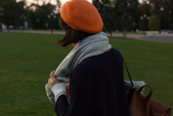 Young stylish woman walking in park in a scarf and orange hat - Photo, Image
