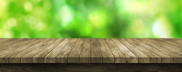 Bulanık yeşil arkaplanı olan tahta masa üstü - Fotoğraf, Görsel