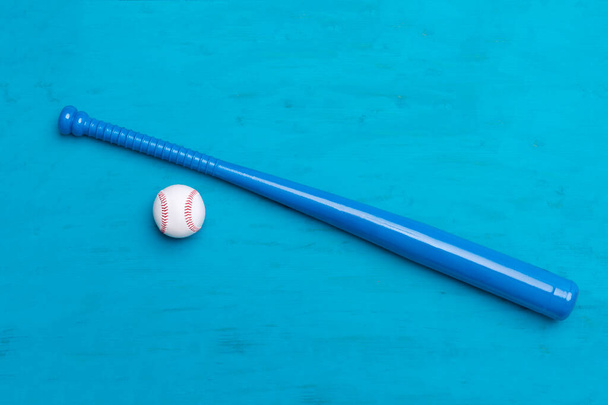 Blauwe honkbalknuppel en bal op blauwe houten achtergrond - Foto, afbeelding