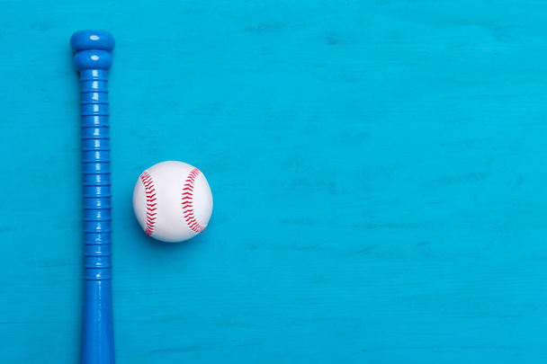 Blauwe honkbalknuppel en bal op blauwe houten achtergrond - Foto, afbeelding