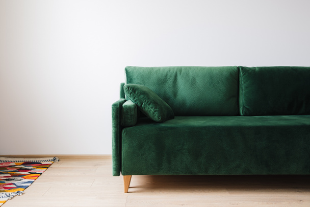 green sofa with pillow near colorful rug on floor - Photo, Image
