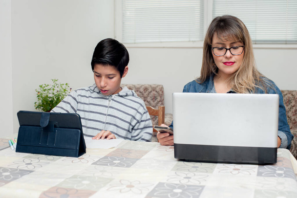 Günlük hayat. Çocuk, annesi bilgisayarın başında çalışırken hareketlerini tabletinde gösteriyor.. - Fotoğraf, Görsel
